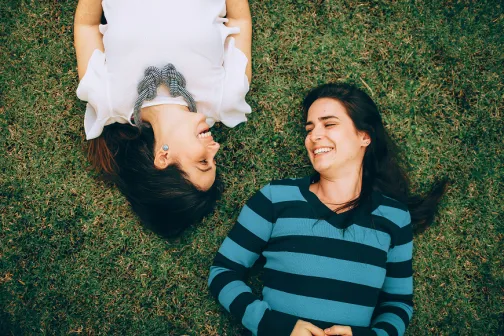 women lying on the grass laughing