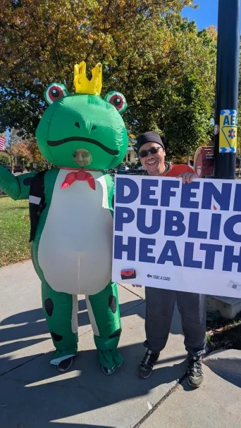man in frog suit and man holding a sign